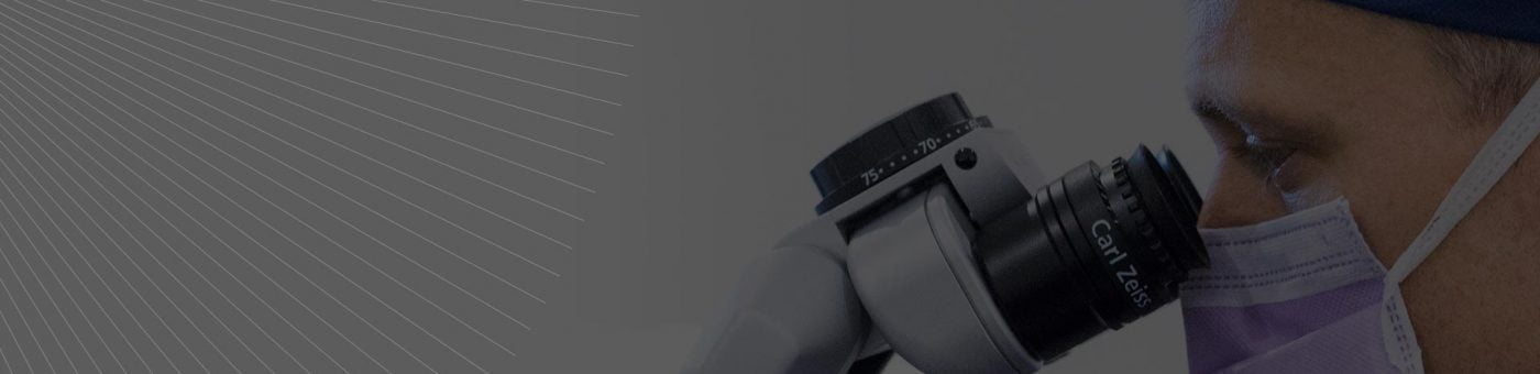 Dr James Genge in surgery looking through the laser microscope